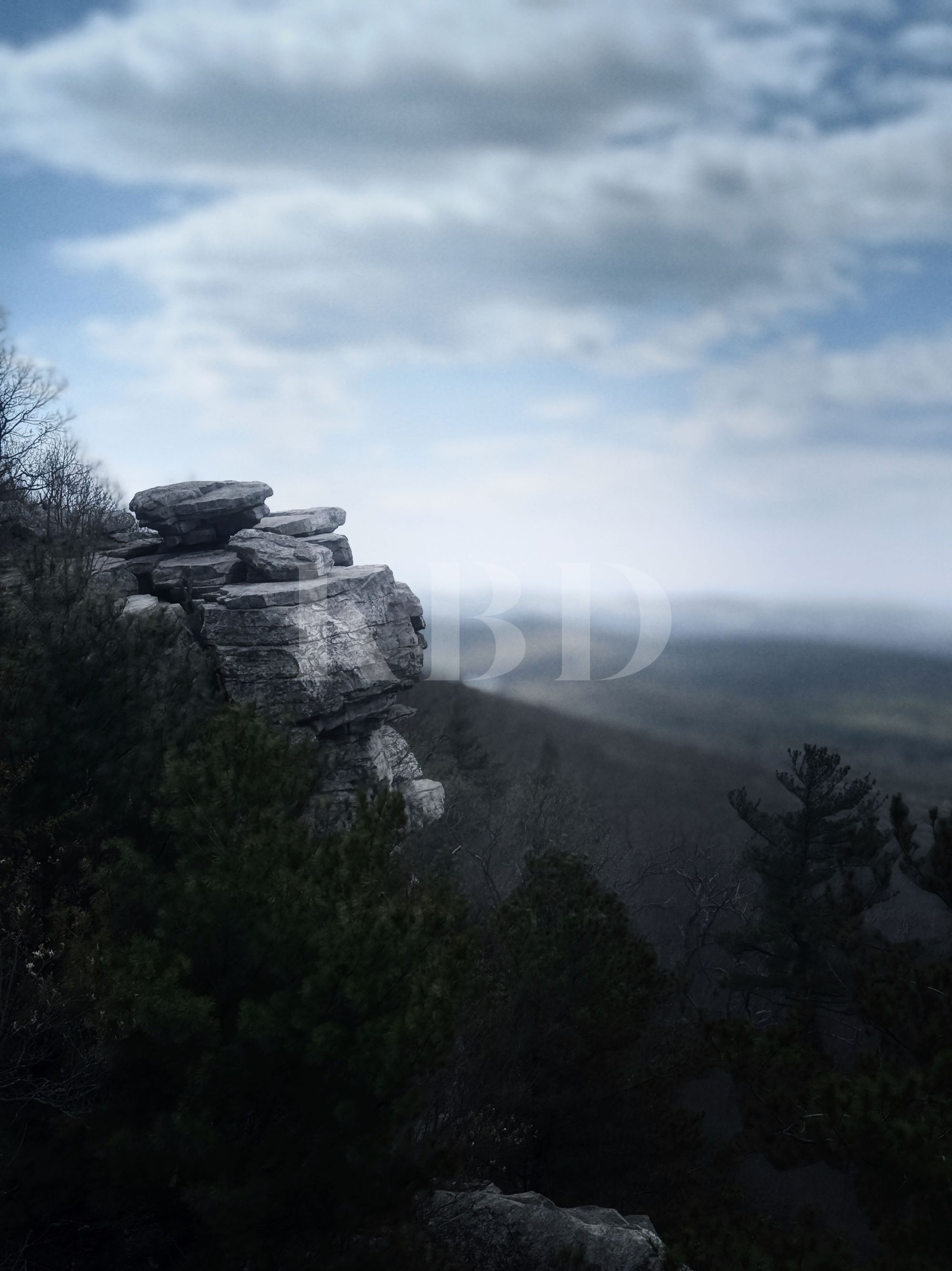 Ancient stacked quartzite rock formation on a dramatic ridge at Greenbrier State Park, South Mountain Maryland, overlooking a misty valley under a moody cloudy sky